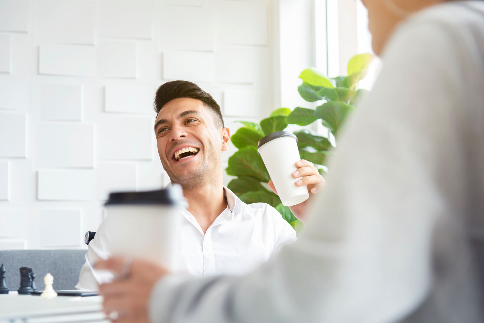 Two colleagues laughing over coffee in a pantry